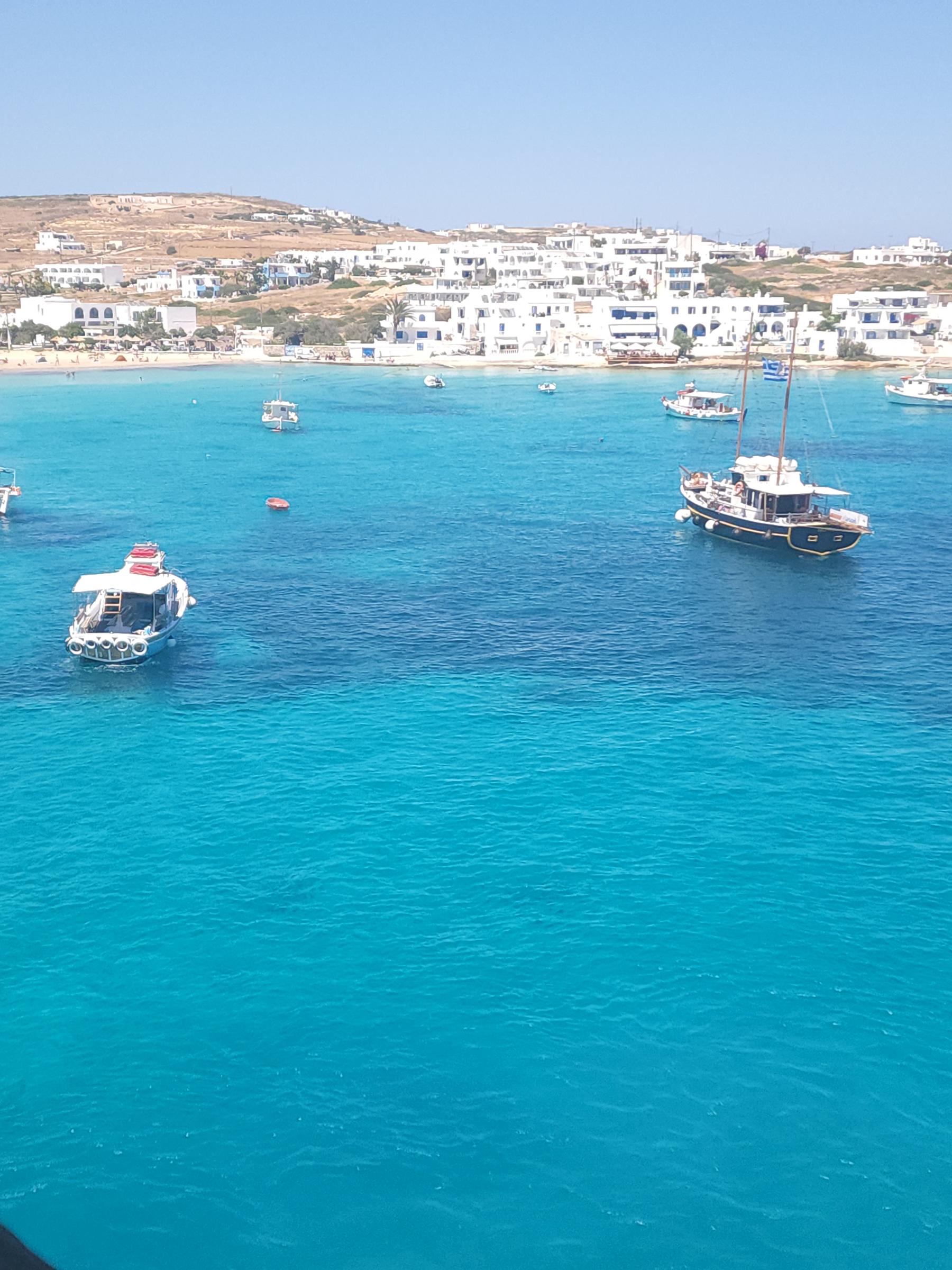 Turquoise water and small boats in front of a whitewashed island village