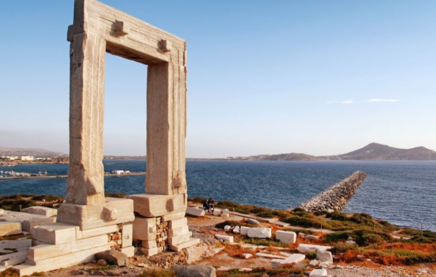 The marble Portara gate on the Naxos waterfront, with the sea and Paros behind