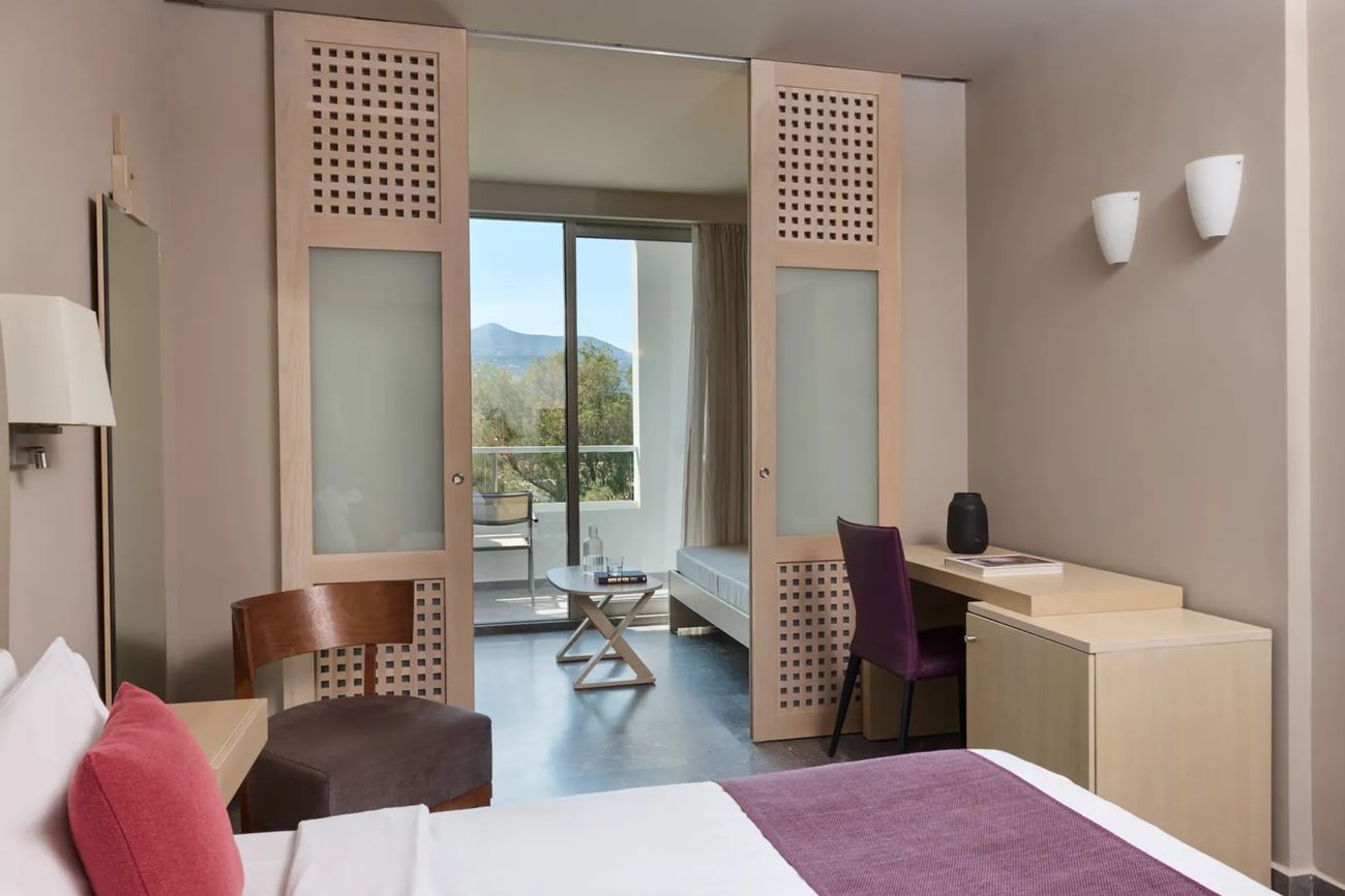 A bright room with sliding wooden screens opening to a balcony and mountain view