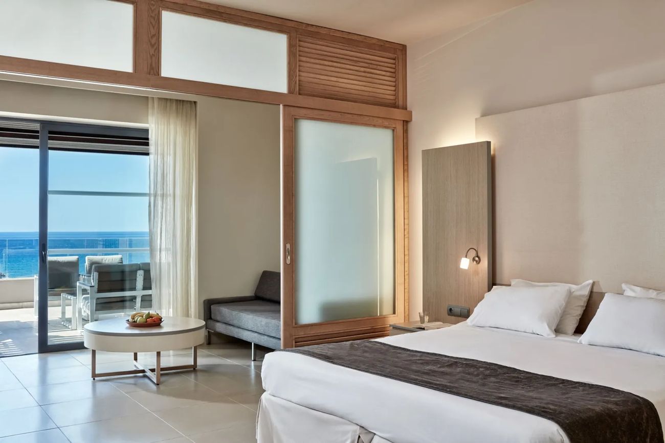 A room with a sea-view balcony, a sofa bed and a round coffee table